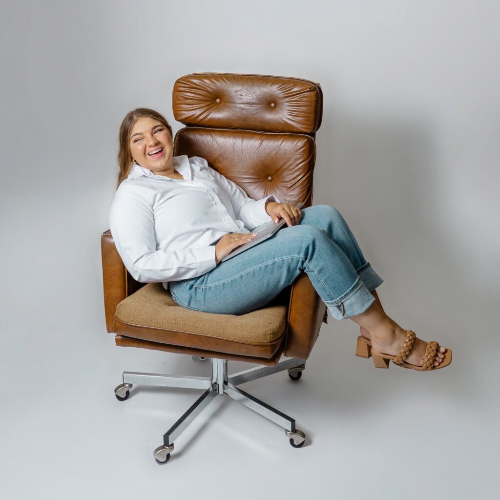 Lilly Bringle sitting on a chair holding a laptop.